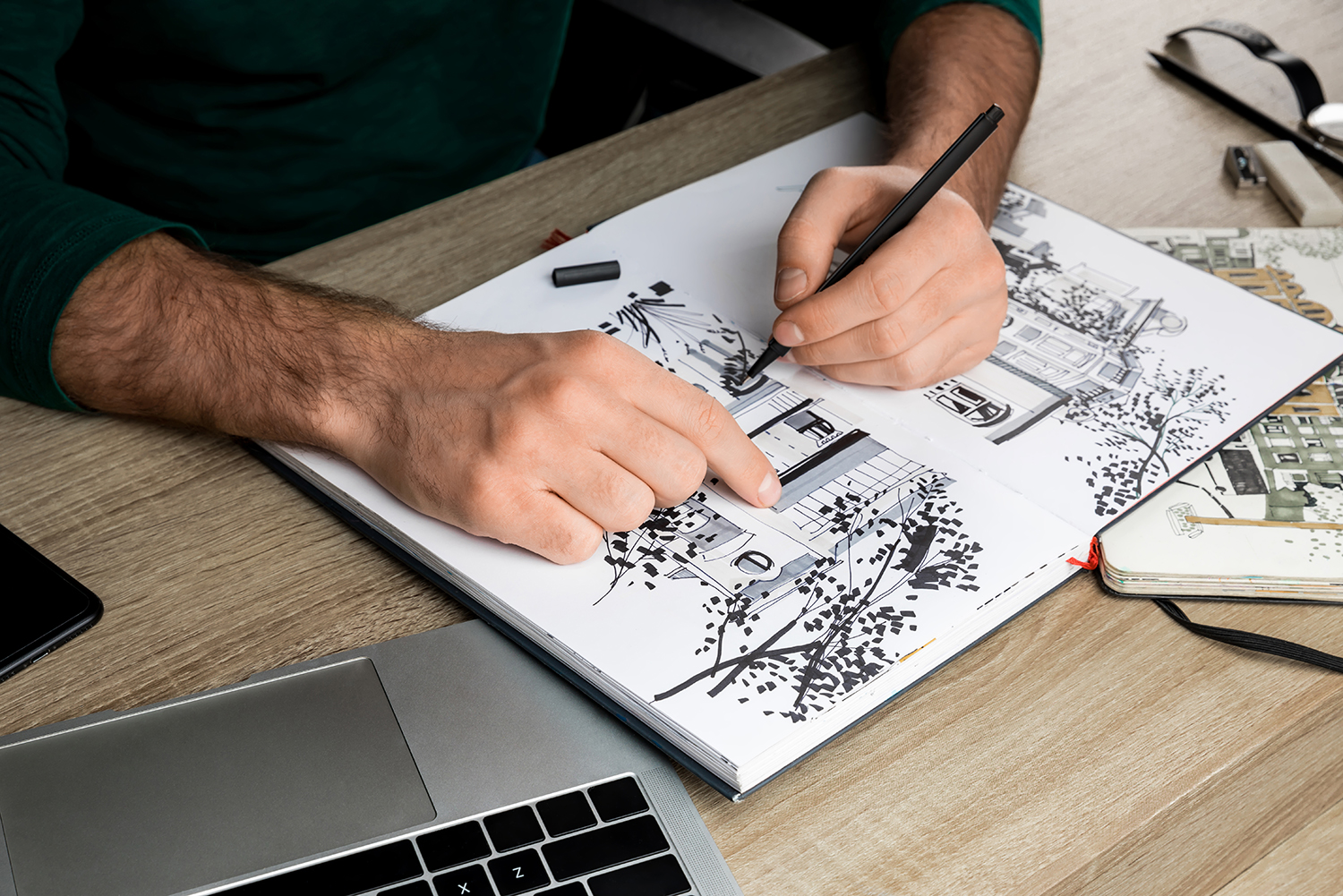 selective focus of mans hands drawing in album on wooden table n
